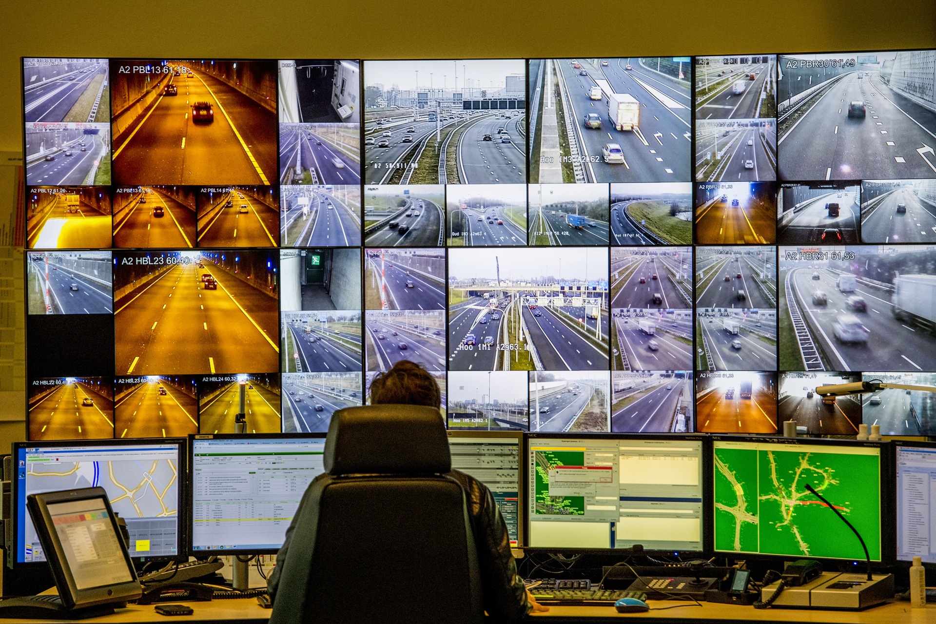 Man werkt achter het bureau en veel schermen voor zich in de verkeerscentrale Utrecht.