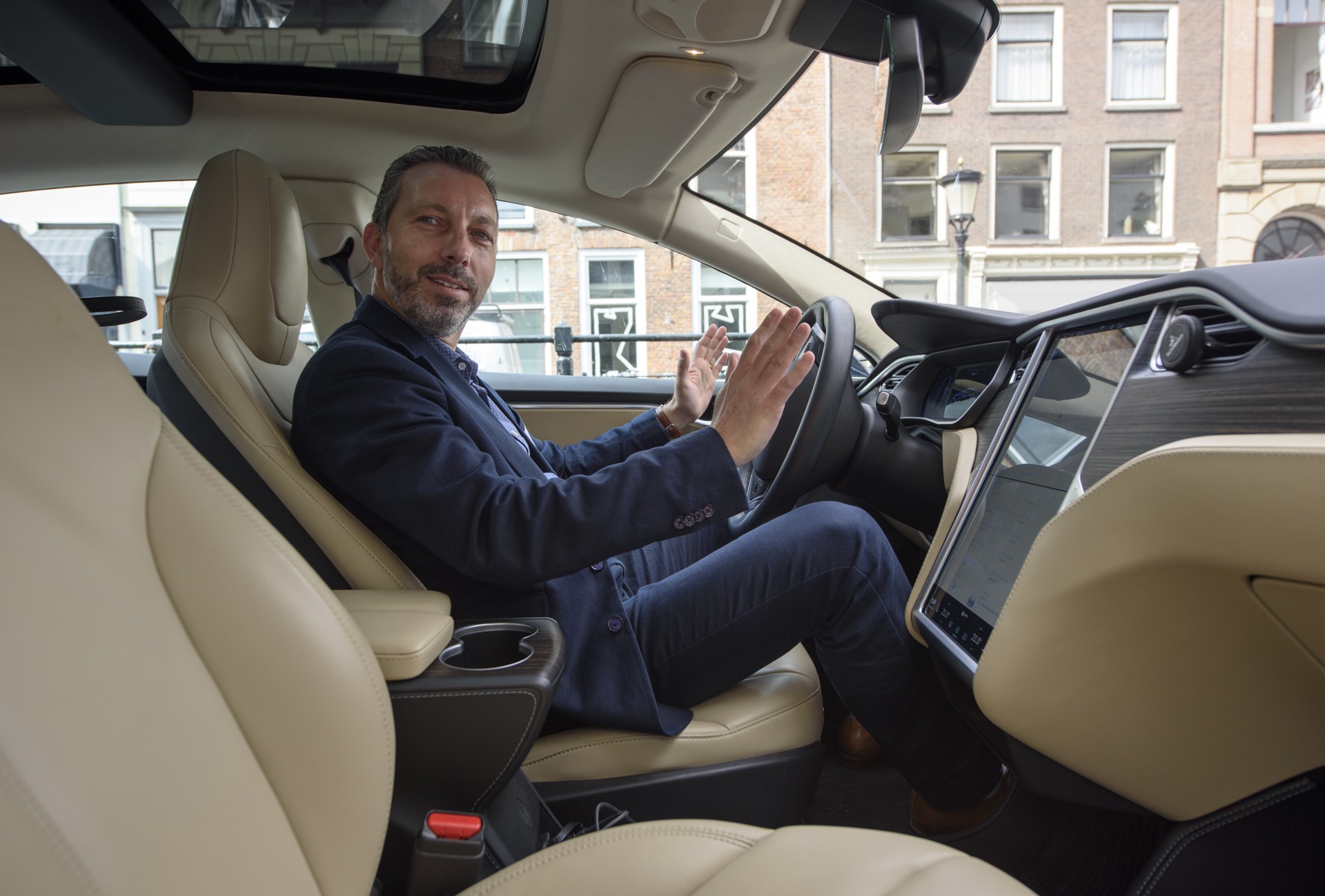 Een man in een Tesla die zijn handen van het stuur haalt