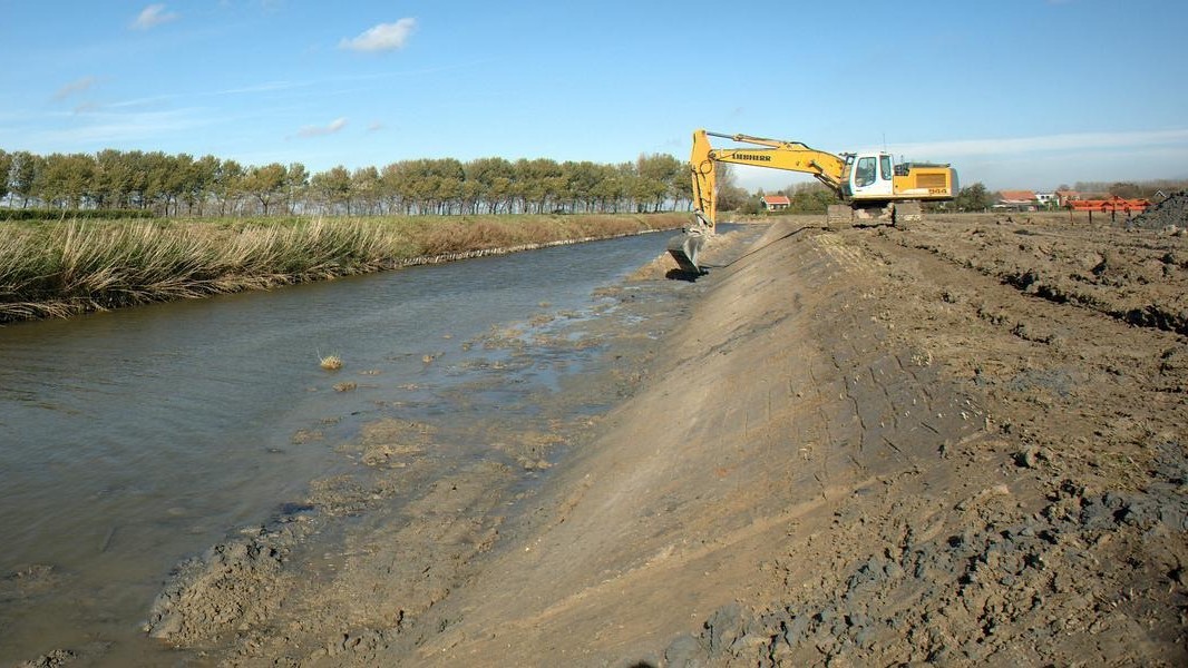 Eem graafmachine die een oever aanlegt bij een waterloop