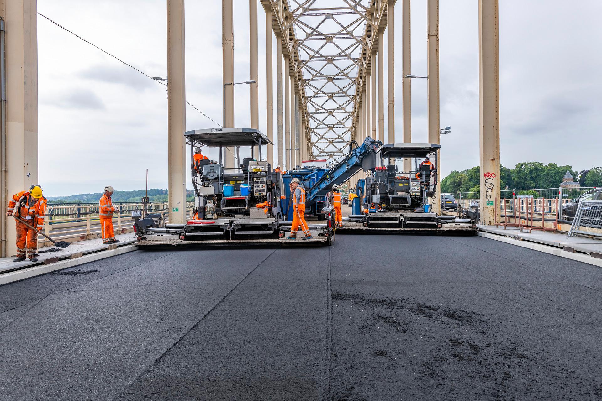 Mensen aan het werk aan het asfalt op een brug.