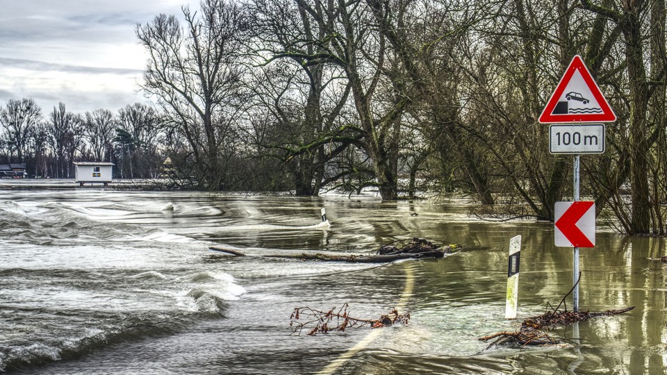 Hoogwater in Limburg met daarop een verkeersbord dat automobilisten waarschuwt voor de kade. De kade zelf is niet meer zichtbaar, want volledig overstroomd.