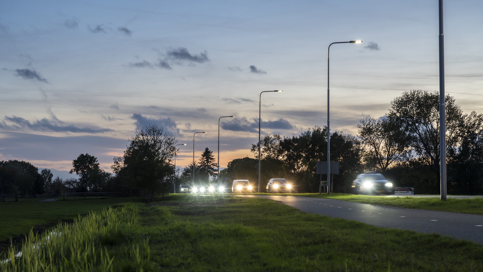 Rijdende auto's met lichten aan in de schemer.