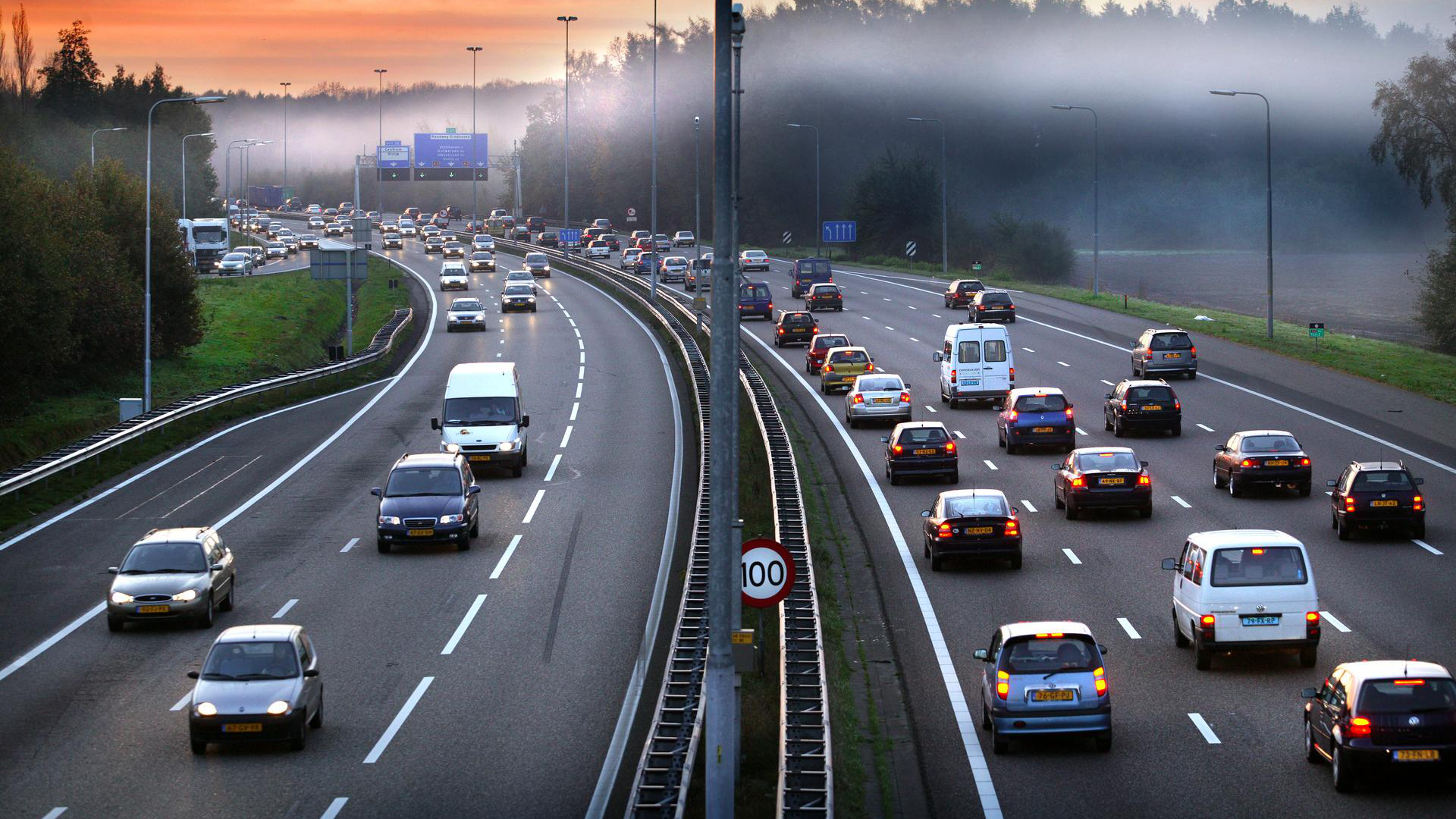 Een drukke snelweg in de schemer met wat lichte mist