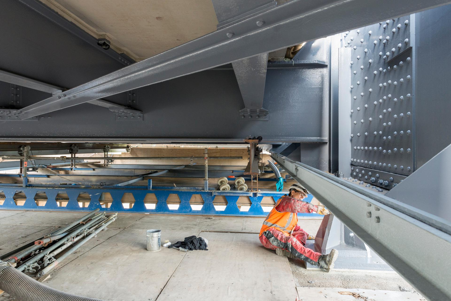 Een wegwerker die in beschermende kleding aan het werk is onder een brug