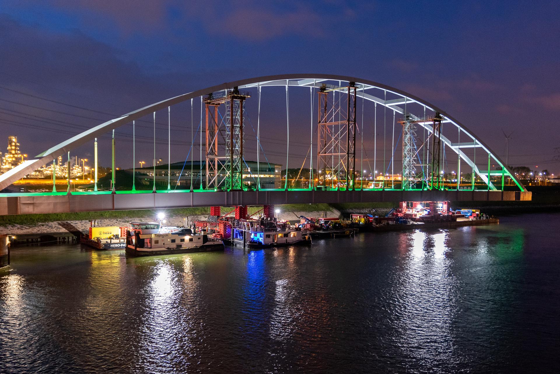 Rijkswaterstaat die in het donker met boten de tijdelijke Suurhoffbrug in de A15 plaatst